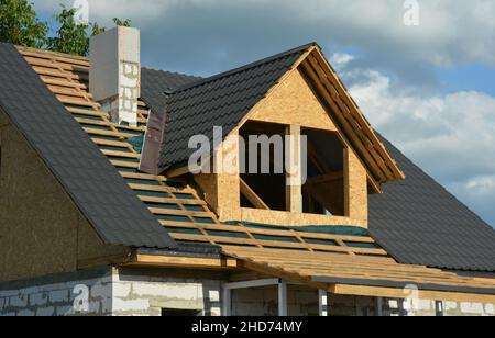 Una casa in costruzione con un primo piano della costruzione del tetto sul palco di incorniciatura del tetto su una barriera al vapore, piastrelle metalliche e INS lampeggiante Foto Stock