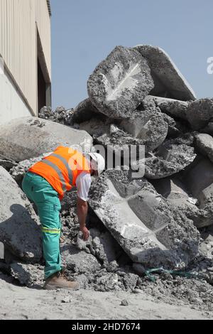 Bahrein. Un responsabile esamina la torta di sale di alluminio prima della lavorazione per recuperare l'alluminio residuo. Foto Stock