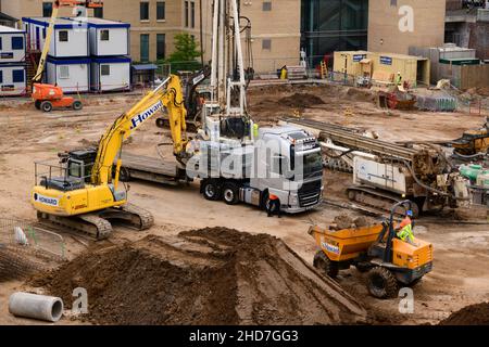 Occupati lavoratori di cantieri edili, veicoli, scarico di escavatori, consegna di materiali da costruzione, cabine per uffici - Hudson Quarter, North Yorkshire Inghilterra UK Foto Stock