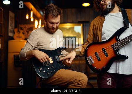 I ragazzi hipster che allenano suonano la chitarra godono di prove Foto Stock