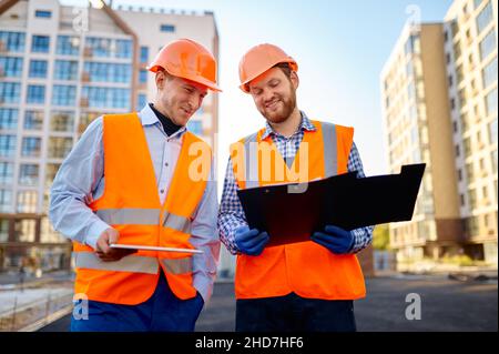 Due sorridenti operai edili che discutono della piantina Foto Stock