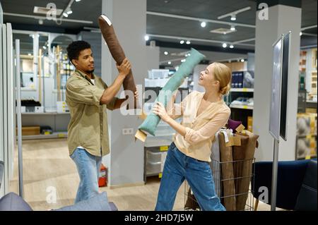 Coppia allegra che combatte con cuscino in negozio Foto Stock