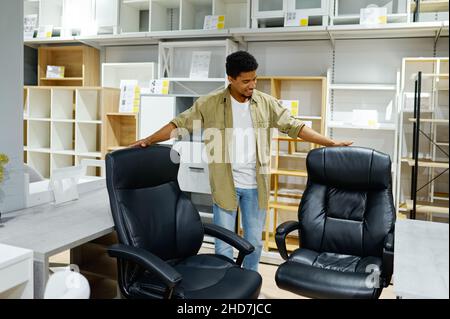 Uomo che sceglie poltrone da ufficio in negozio di mobili Foto Stock