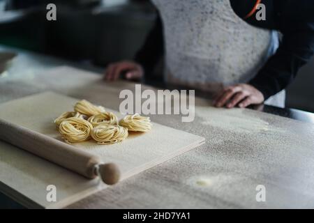 Donna prepara la pasta tradizionale all'interno della fabbrica italiana - Focus sulla pasta Foto Stock