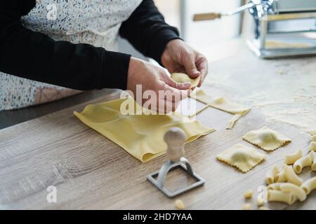 Donna prepara ravioli freschi all'interno della fabbrica di pasta - Focus sulla mano sinistra Foto Stock