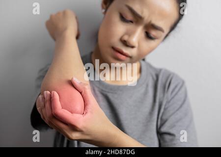 Donne con dolore al gomito. Dolore acuto in un gomito. Giovane donna tiene sopra al gomito. Foto Stock