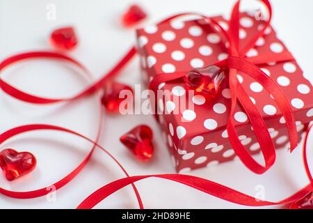 Confezione regalo rossa con punti bianchi su sfondo bianco con arco e nastro Foto Stock