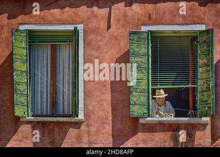 Uomo che guarda il mondo passare dalla sua finestra a Firenze Italia Europa Foto Stock