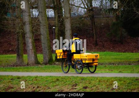 Un postino consegna il suo trasporto. Foto Stock