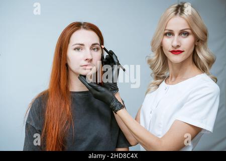 Il padrone estetician fa il markup del sopracciglia che tatuing, le donne prima di applicare il trucco permanente, il trucco permanente dell'occhio e la procedura di correzione del sopracciglio. La ragazza felice del cliente è molto soddisfatta Foto Stock