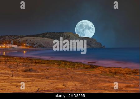 Luna piena sulla costa rocciosa di Praia da Luz, Algarve, Portogallo, Europa Foto Stock