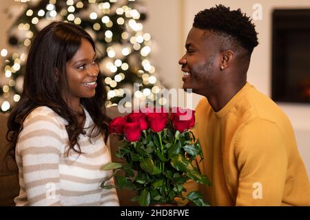 Il marito nero che dà le rose alla moglie su San Valentino a casa Foto Stock