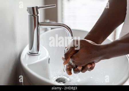Cropped Shot of Black Guy lavarsi le mani con sapone Indoor Foto Stock