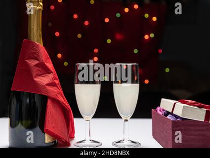 due bicchieri di champagne e un regalo con sfondo sfocato. giorno di san valentino, giorno delle madri. Foto Stock