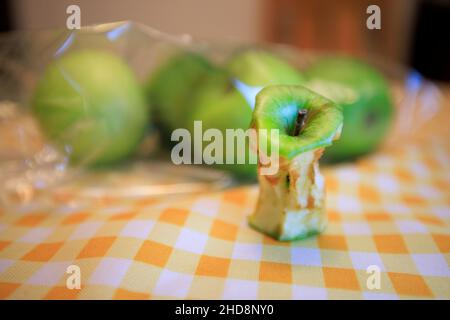 Un nocciolo di mela marcio accanto ad alcune mele fresche Foto Stock