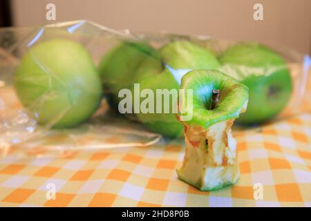 Un nocciolo di mela marcio accanto ad alcune mele fresche Foto Stock