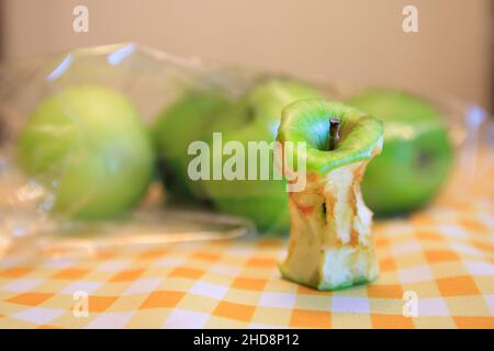 Un nocciolo di mela marcio accanto ad alcune mele fresche Foto Stock