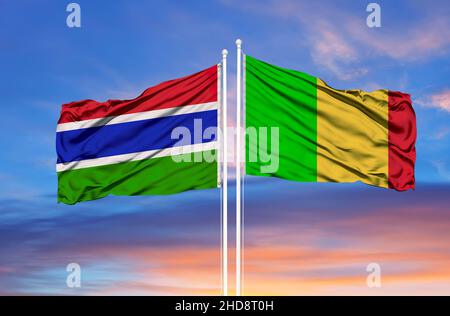 Gambia e Mali due bandiere su flagpoli e cielo nuvoloso blu Foto Stock