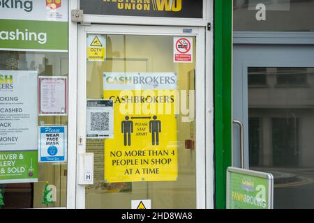 Slough, Berkshire, Regno Unito. 30th dicembre 2021. Un segno sociale di allontanamento in un negozio di cashbroker a Slough. Credit: Maureen McLean/Alamy Foto Stock