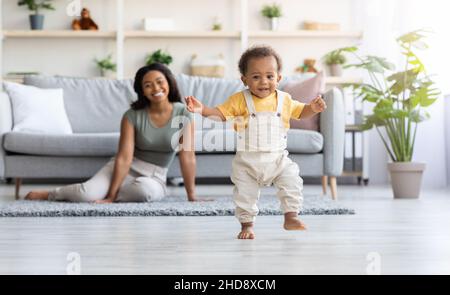 Primi passi. Adorabile bambino nero che cammina nel soggiorno di casa Foto Stock