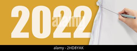 la mano di affari disegna la corda per aprire la carta sgualcita mostrando 2022 nuovo commercio su sfondo giallo della carta come concetto. Foto Stock