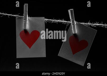 Un clothesline di iuta, due pioli di vestiti (clip), due cuori rossi su due con le schede di nota per trasmettere un messaggio per amore, valentine e passione, stringa di cuore Foto Stock