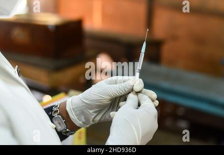 Un operatore sanitario prepara una dose di vaccino COVID-19 per inoculare uno studente durante una campagna di vaccinazione per le persone di età compresa tra i 15-18 e i 24 anni in una scuola di Guwahati, Assam, India il 3 gennaio 2022. L'India ha rilevato più di 1.700 casi di variante Omicron di nuova infezione da coronavirus. Foto Stock