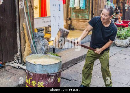 FENGHUANG, CINA - 13 AGOSTO 2018: Produttore di caramelle con mazzuolo in legno nella città vecchia di Fenghuang, provincia di Hunan, Cina Foto Stock