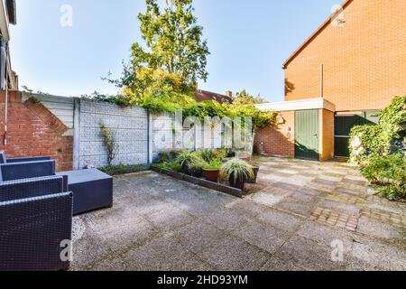 Piccolo cortile con molta vegetazione e pareti in mattoni Foto Stock