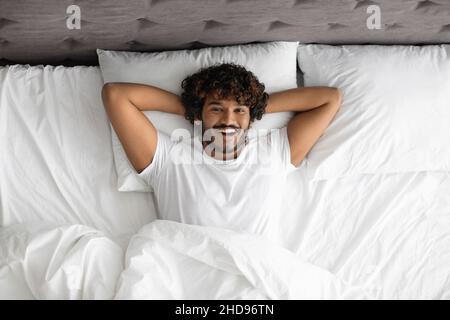 Rilassato uomo indiano godendo felice mattina a letto Foto Stock