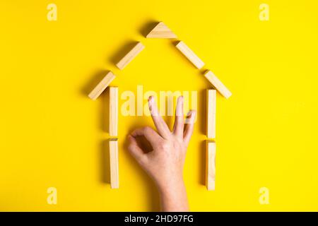 Vista dall'alto della mano del bambino close up blocchi di costruzione che mostrano ok, casa, capanna di legno Foto Stock