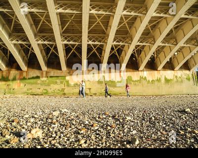 Una famiglia che cammina lungo la riva del Tamigi sotto le travi in acciaio del Blackfriars Bridge, Londra, Inghilterra, Regno Unito. Foto Stock