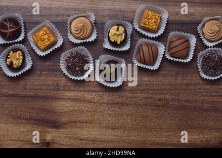 Varie praline di cioccolato giacciono in cima su uno sfondo di legno Foto Stock