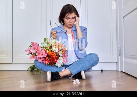 Triste turbata donna di mezza età con un bouquet di fiori Foto Stock