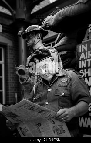 Mono close up of wartime, 1940 ARP warden (Air raid Precauzioni) lettura giornale d'epoca, Severn Valley Heritage Railway 1940s WW2 evento estivo UK. Foto Stock