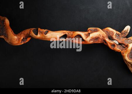 Curvo testurizzato legno serpente di colore marrone con texture su sfondo nero con spazio libero. Foto Stock