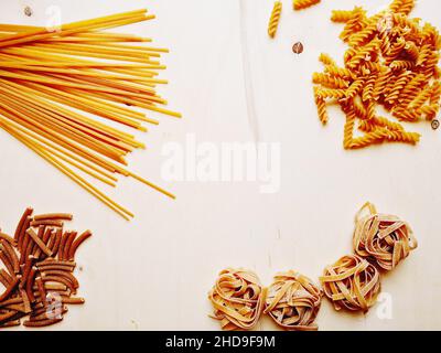 Piatto posato con diverse forme di pasta posto su un asse di legno, spazio copia al centro Foto Stock