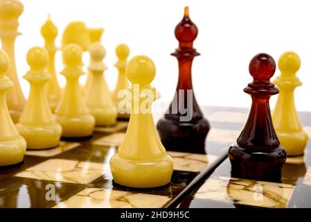 Ambra naturale diversi pezzi di scacchi figure in piedi sulla tavola di perle in bianco. Primo piano del concorso di concetto di gioco, Torneo classico di confronto. Foto Stock