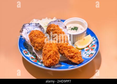 Piatto di crostacei giapponesi di ostriche fritte in pastella e fritte, con l'aggiunta di albumi e pangrattato chiamati kaki-furai o kaki friggere servito nella loro cenere Foto Stock