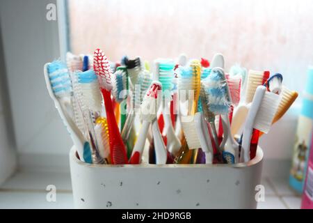 Una selezione di spazzolini colorati in plastica in una pentola in un bagno a Chichester, West Sussex, Regno Unito. Foto Stock