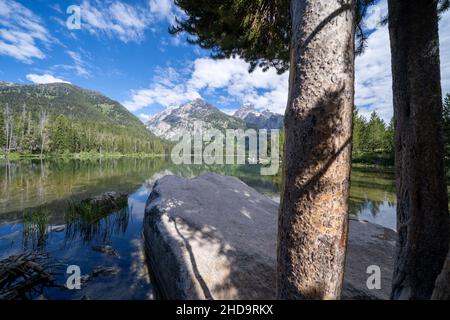 Lago Taggart nel Parco Nazionale Grand Teton, incorniciato da rocce in una mattinata soleggiata e tranquilla Foto Stock