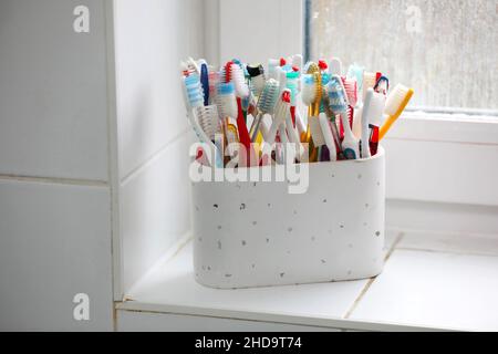 Una selezione di spazzolini colorati in plastica in una pentola in un bagno a Chichester, West Sussex, Regno Unito. Foto Stock