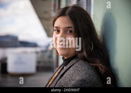 Ritratto di una ragazza sorridente. La ragazza adolescente felice e calma sta appoggiando con la schiena contro un muro. Bella ragazza nordafricana. Felice giovinezza Foto Stock