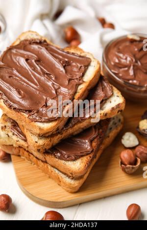 Tavola di pane con pasta di cioccolato e nocciole sul tavolo, primo piano Foto Stock