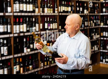 l'uomo sceglie tra vino rosso e bianco Foto Stock
