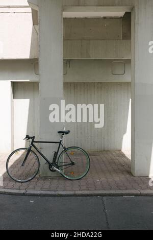 Scatto verticale di una bicicletta parcheggiata sotto un edificio bianco Foto Stock