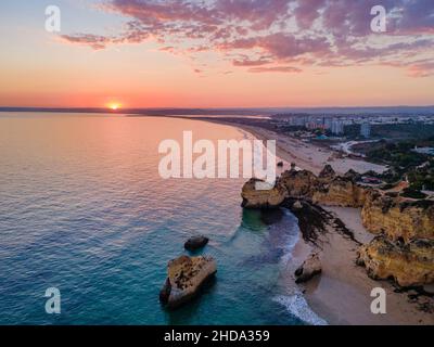 Vista aerea del tramonto della bella Praia dos Tres Irmaos (Tree Brothers Beach) in Alvor, famosa destinazione turistica nella costa occidentale dell'Algarve, Portuga Foto Stock