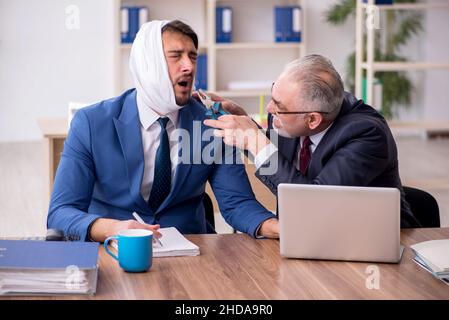 Giovane impiegato d'affari che soffre di mal di denti in ufficio Foto Stock