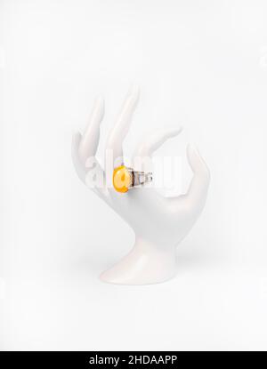 Mano bianca in plastica con anello in argento e ambra cinese su sfondo bianco Foto Stock