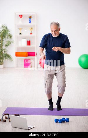 L'uomo anziano fa esercizi sportivi a casa Foto Stock